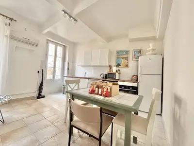 a kitchen with a table with chairs and a refrigerator at Cannes 2 Bedroom Apartment - 19JDR2 in Cannes