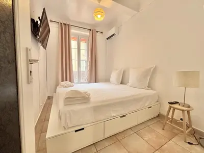 a white bedroom with a bed and a window at Cannes 2 Bedroom Apartment - 19JDR2 in Cannes
