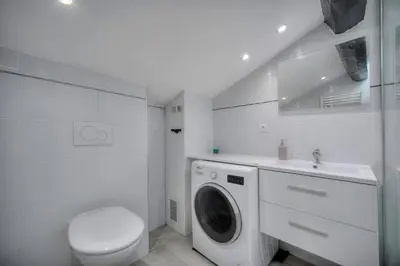 a white bathroom with a washing machine and a toilet at Studio Cannes in Cannes