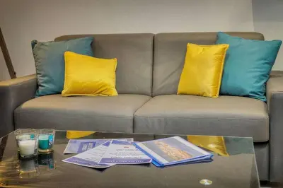 a couch with yellow and blue pillows and a coffee table at Le 8 - Cannes in Cannes