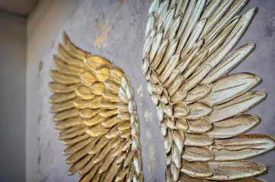 a gold statue of wings on a wall at Le 8 - Cannes in Cannes