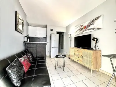 a living room with a black couch and a kitchen at Cannes 1 Bedroom Apartment - CC1 in Cannes