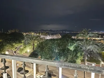 a view of a city at night with palm trees at 39m2 Croisette, terrasse, vue mer, garage in Cannes