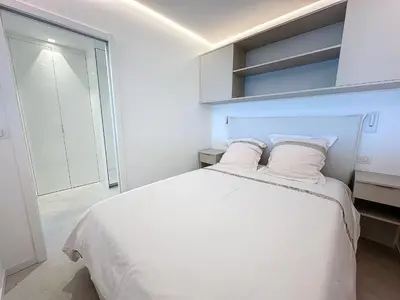 a white bedroom with a large bed with white pillows at 39m2 Croisette, terrasse, vue mer, garage in Cannes