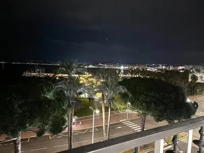 a view of a parking lot with palm trees at night at 39m2 Croisette, terrasse, vue mer, garage in Cannes
