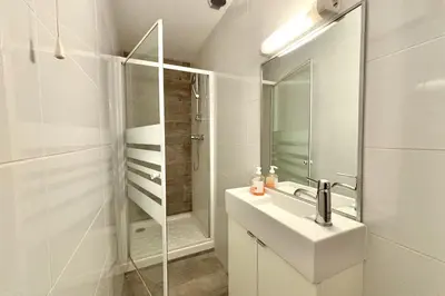 a white bathroom with a sink and a shower at Luminous T2 on the seafront in Cannes