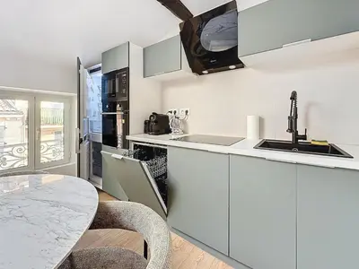 a kitchen with white cabinets and a table at 54m2 hypercenter, face Palais des Festivals in Cannes