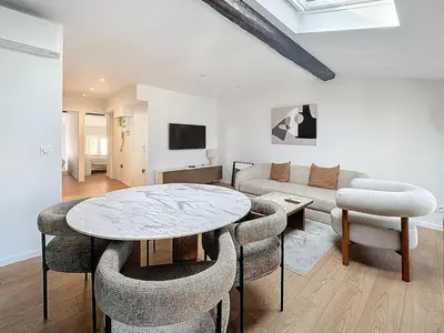 a living room with a table and chairs and a couch at 54m2 hypercenter, face Palais des Festivals in Cannes
