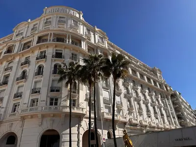 a large white building with palm trees in front of it at Residence Palais Miramar in Cannes