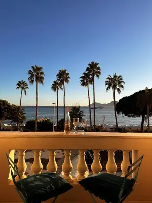 a bottle of wine sitting on a balcony overlooking the beach at Residence Palais Miramar in Cannes