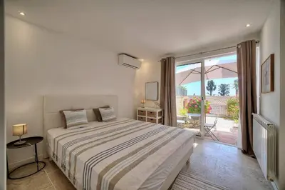a white bedroom with a bed and a balcony at Kathleen CANNES-GOLFE JUAN in Vallauris