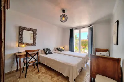 a bedroom with two beds and a table and a mirror at Kathleen CANNES-GOLFE JUAN in Vallauris