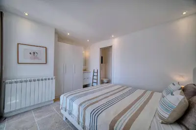 a white bedroom with a bed and a chair at Kathleen CANNES-GOLFE JUAN in Vallauris