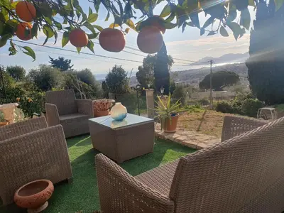 a patio with wicker chairs and a table on the grass at chambre jaccuzi vue mer in Le Cannet