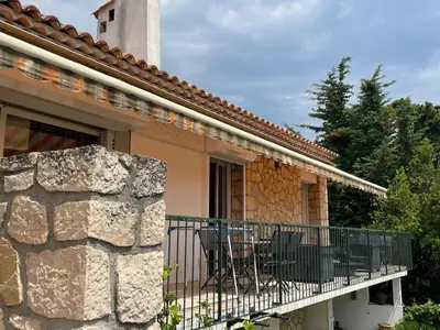 a house with a balcony with chairs and a stone wall at Architect's house 100m2 sea view, terraces 35m2 in Le Cannet