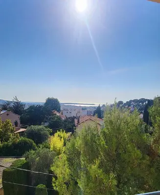 a view of a city with the sun in the sky at 3 pièces cocon dans les hauteurs de Cannes vue mer in Le Cannet