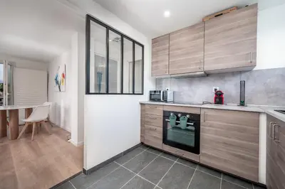 a kitchen with wooden cabinets and a stove at 3 pièces cocon dans les hauteurs de Cannes vue mer in Le Cannet