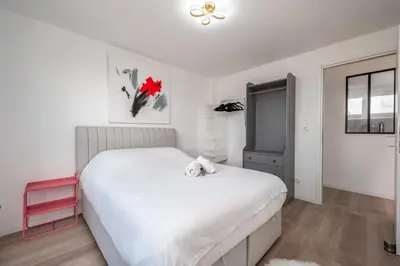 a bedroom with a white bed and a red stool at 3 pièces cocon dans les hauteurs de Cannes vue mer in Le Cannet