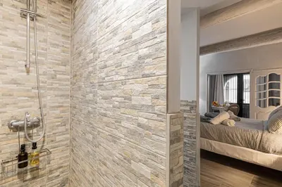 a bathroom with a stone wall and a shower at Hotel particulier Croisette in Cannes