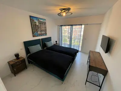 a bedroom with a bed and a table and a television at Modern Chic Seaview Appartement in Cannes
