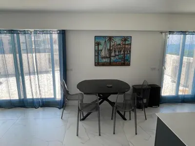 a table and chairs in a room with windows at Modern Chic Seaview Appartement in Cannes