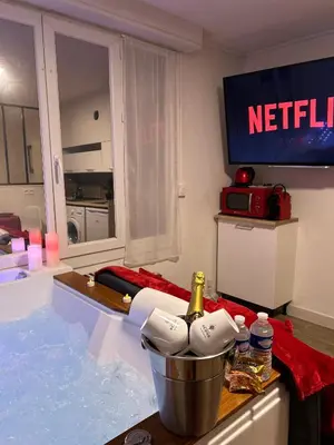 a bath tub filled with water with a bottle of champagne at Romantic Room - Jaccuzi Privé -Appartement Cannes in Cannes