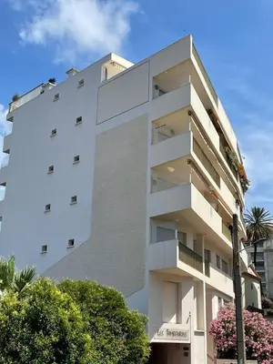a tall white building with trees in front of it at Mistral Seaside Studio - 200m de la Plage in Cannes