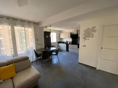 a living room with a couch and a table and a kitchen at Appartement MIRAMAR 5 couchages in Cannes