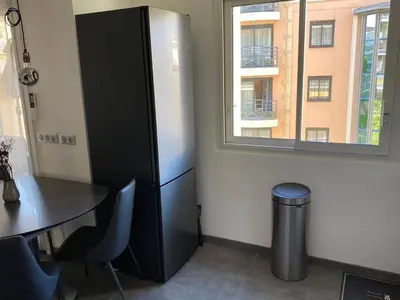 a black refrigerator next to a table and a window at Appartement MIRAMAR 5 couchages in Cannes