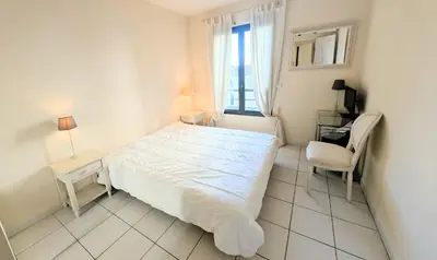 a white bedroom with a bed and a chair at Ref FLORIAN by Palmes dProperties in Cannes