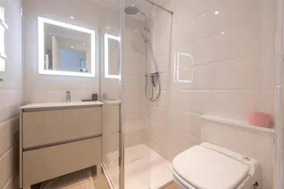 a white bathroom with a shower and a toilet at Riviera Escape – Sea View, Pool & Tennis in Cannes