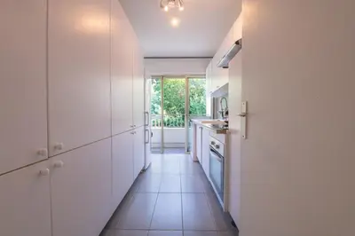 a kitchen with white cabinets and a long hallway at Riviera Escape – Sea View, Pool & Tennis in Cannes
