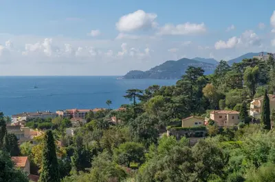 a town on a hill with the ocean in the background at Riviera Escape – Sea View, Pool & Tennis in Cannes