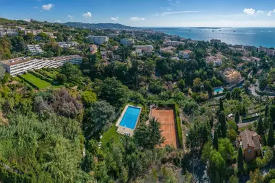 an aerial view of a city with a tennis court and the ocean at Riviera Escape – Sea View, Pool & Tennis in Cannes