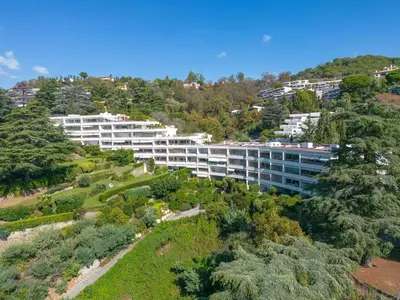 an aerial view of a building on a hill with trees at Riviera Escape – Sea View, Pool & Tennis in Cannes