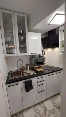 a small kitchen with white cabinets and a sink at Studio F1 avec jardin, proche du Palais des festivals et des plages in Cannes