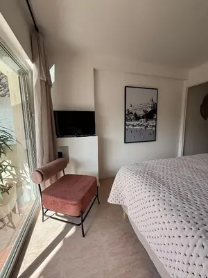 a bedroom with a bed and a chair and a window at Studio au California Palace in Cannes