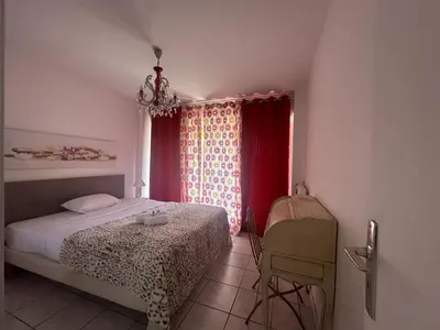 a bedroom with a bed and a window with red curtains at Abou1895 in Cannes