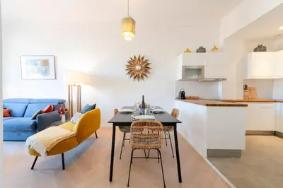 a kitchen and living room with a table and chairs at Modern 2-Br Apartment with Balconies 3 Min from Palais des Festivals in Cannes