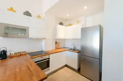 a kitchen with white cabinets and a stainless steel refrigerator at Modern 2-Br Apartment with Balconies 3 Min from Palais des Festivals in Cannes