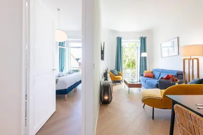 a living room with a blue couch and a bedroom at Modern 2-Br Apartment with Balconies 3 Min from Palais des Festivals in Cannes
