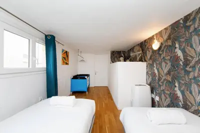 a room with two beds and a wall with floral wallpaper at Immogroom - Maisonnette - T3 - A/C - Wifi in Cannes