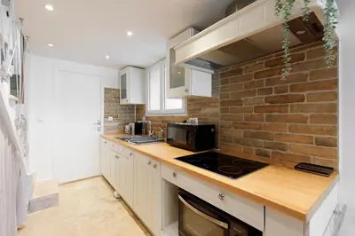 a kitchen with white cabinets and a brick wall at Immogroom - Maisonnette - T3 - A/C - Wifi in Cannes