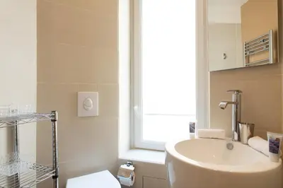 a bathroom with a sink and a toilet and a window at Le Cosy YourHostHelper in Cannes
