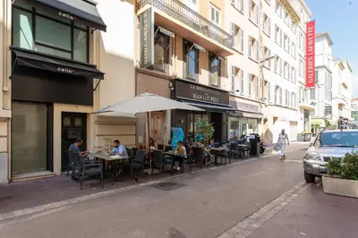 a group of people sitting at tables on a city street at Le Cosy YourHostHelper in Cannes