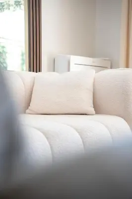 a white couch with a pillow on top of it at Luxueux Appartement avec Jardin Suspendu Vue Mer 10 min du Palais Cannes in Cannes