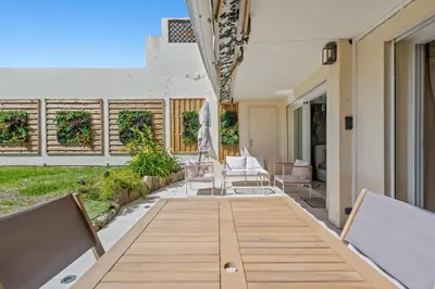 an outdoor dining area with a wooden table and chairs at Luxueux Appartement avec Jardin Suspendu Vue Mer 10 min du Palais Cannes in Cannes