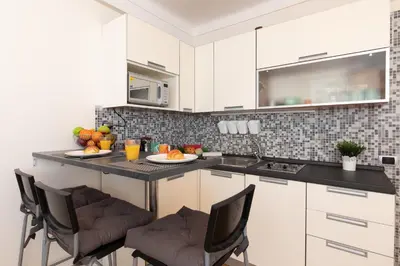 a kitchen with white cabinets and a island with chairs at Pelige 3 YourHostHelper in Cannes