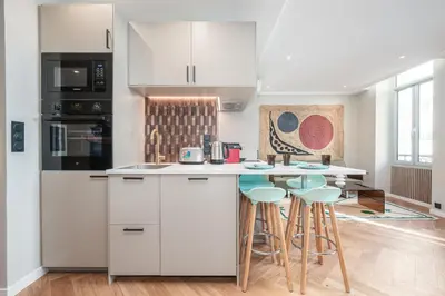 a kitchen with white cabinets and bar stools at Bel appartement centre Cannes 1min de la Croisette in Cannes
