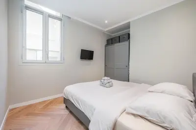 a white bedroom with a bed and a window at Bel appartement centre Cannes 1min de la Croisette in Cannes